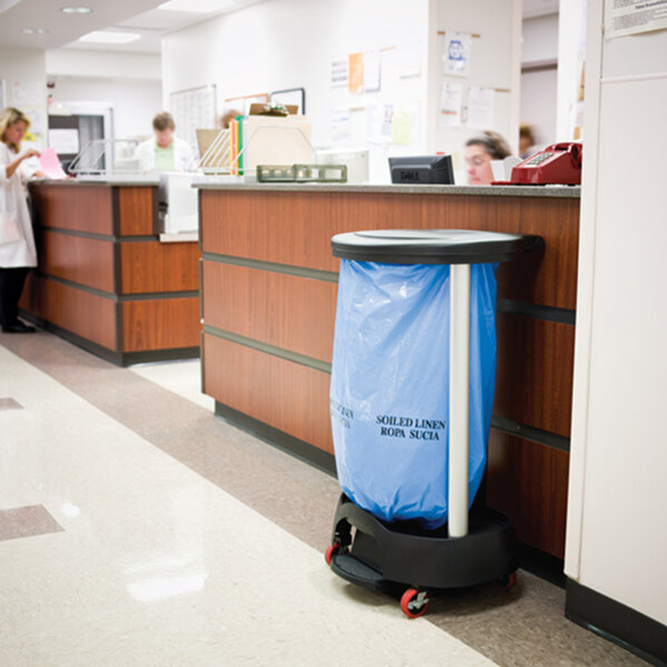 A black Rubbermaid linen hamper on a cart in a hospital.