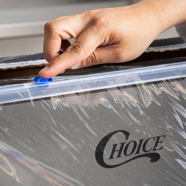 A close-up of a hand using a blue Choice Safety Slide Cutter to open plastic wrap.