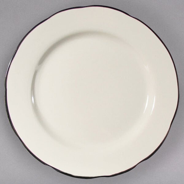 A CAC ivory china plate with scalloped edges and a black rim.
