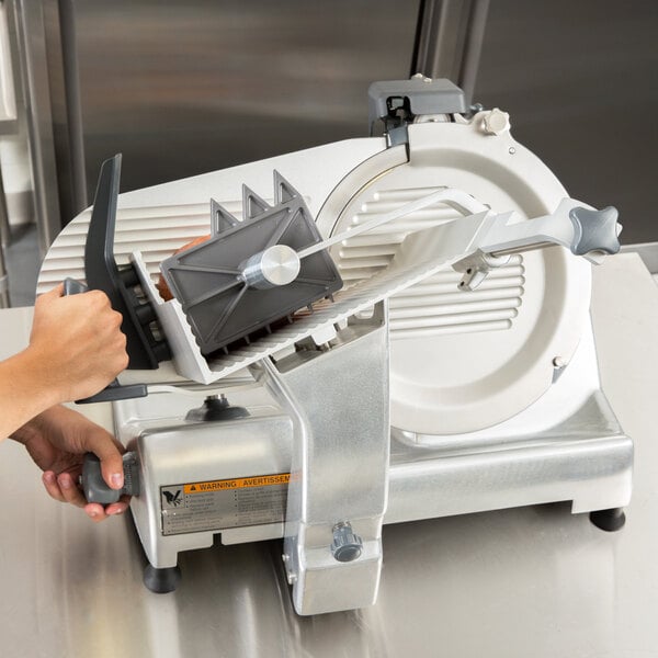 A person using a Hobart meat slicer.