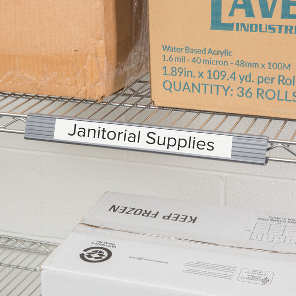 A Metro shelf with gray label holder and boxes labeled "Janitorial Supplies" on it.