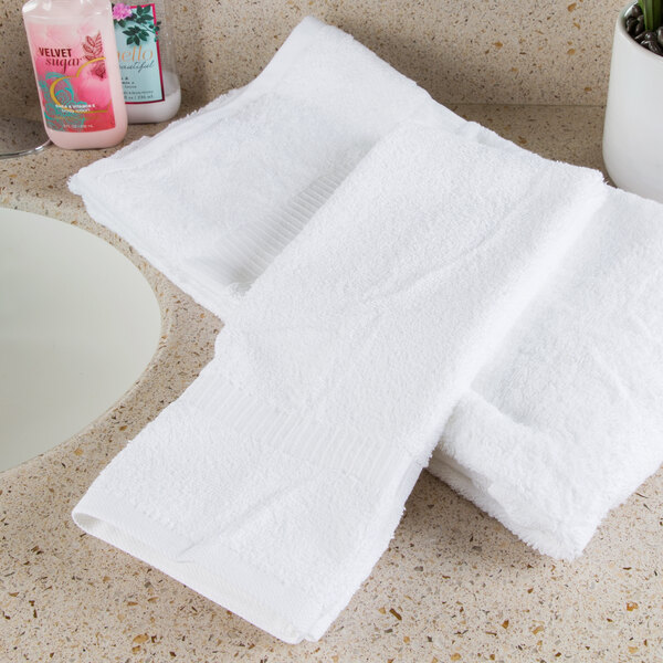 A set of white Oxford Belleeza hand towels on a counter.