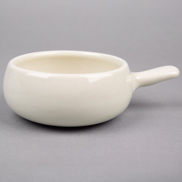 A close-up of a Hall China ivory side handle soup bowl.
