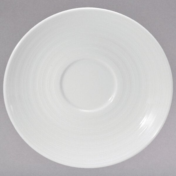 A white porcelain saucer with a circular pattern on it.