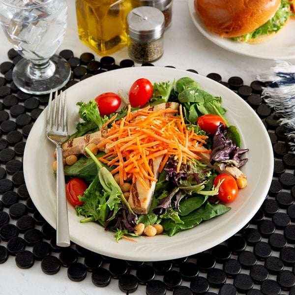 A Oneida cream white china plate with salad, chicken, and vegetables.