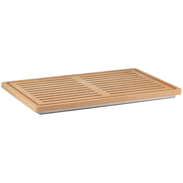A wooden Frilich bread cutting board with a stainless steel reservoir on a table in a home kitchen.