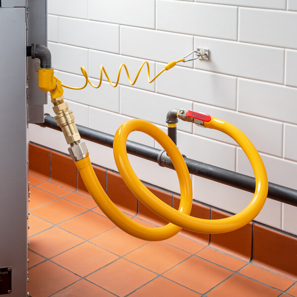 A yellow hose with a red label attached to a black pipe.