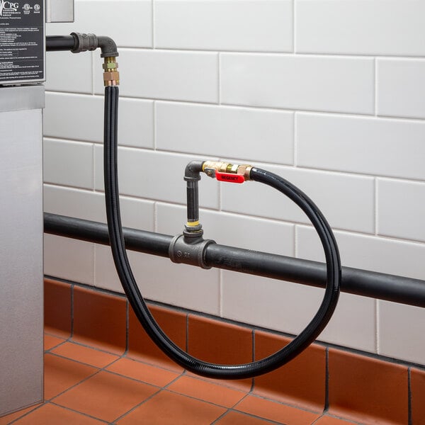 A black Regency gas connector hose kit connected to a metal pipe.