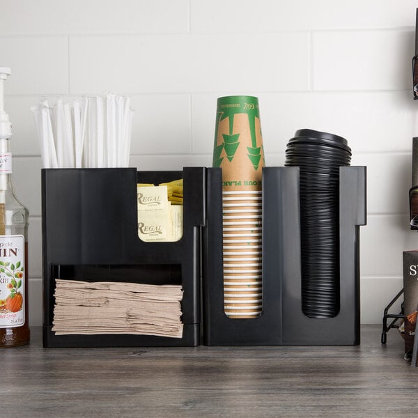 A black Choice countertop cup holder with a stack of paper cups.
