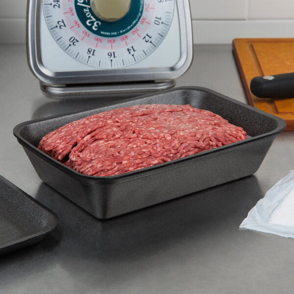 A black CKF foam meat tray with ground meat on it in front of a scale.