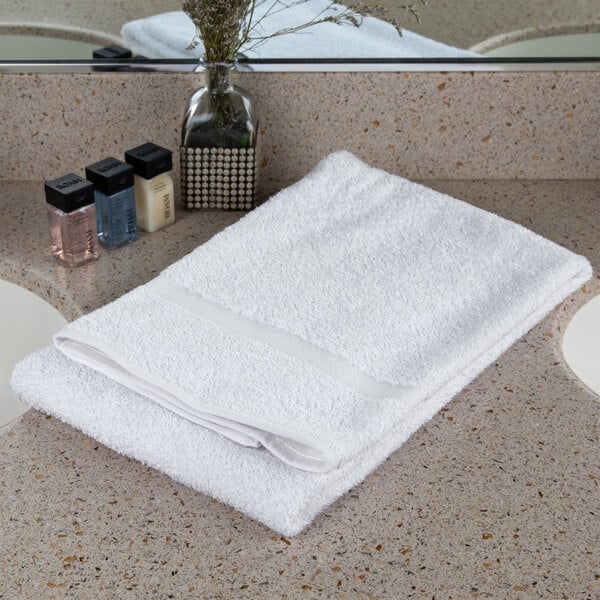 An Oxford Bronze white towel with a cam border on a counter.
