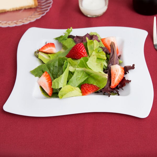 A white Fineline square plastic plate with a salad of strawberries and lettuce.