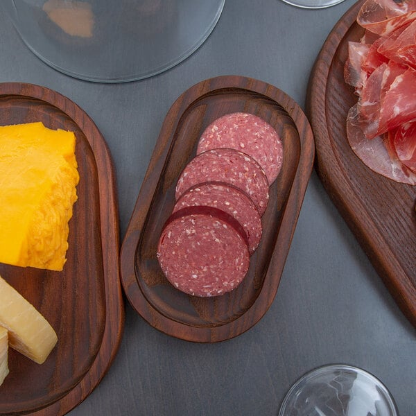An American Metalcraft ash wood serving board with slices of meat and cheese on it.