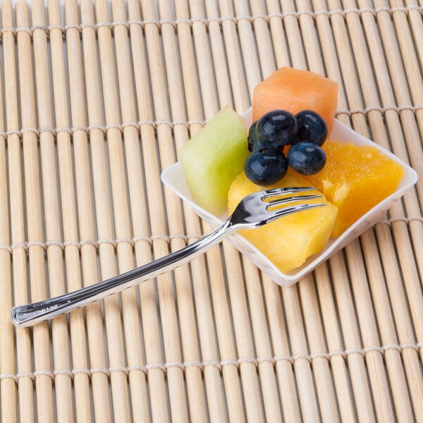 A Fineline Tiny Tines silver plastic tasting fork in a bowl of fruit.