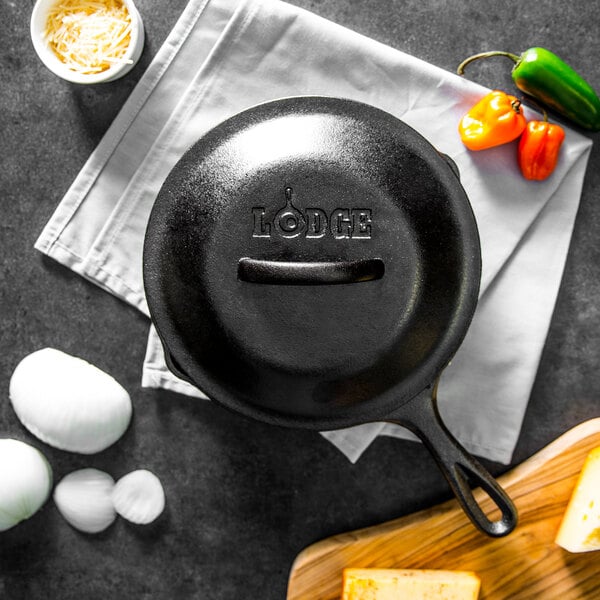 A black Lodge cast iron skillet filled with eggs and cheese on a cutting board.