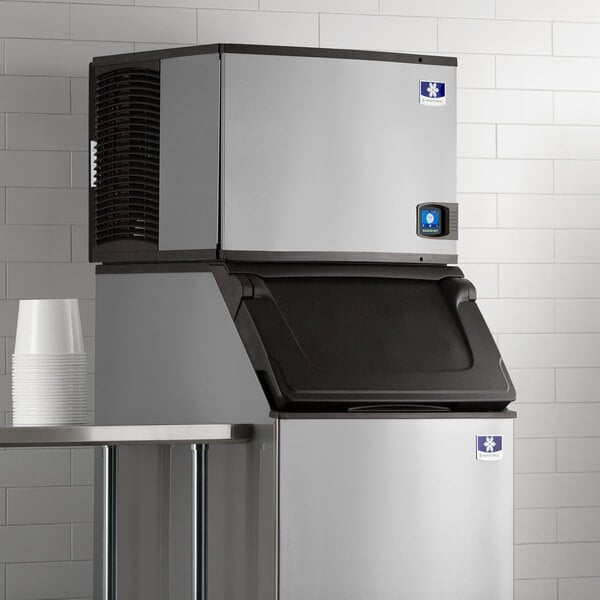 A large stainless steel Manitowoc Indigo NXT air cooled ice maker on a table.