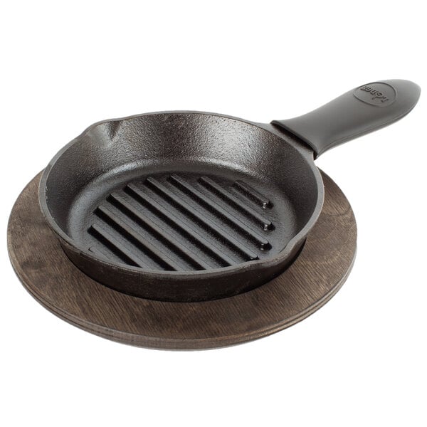 A Lodge cast iron grill pan with a black silicone handle holder on a wooden surface.