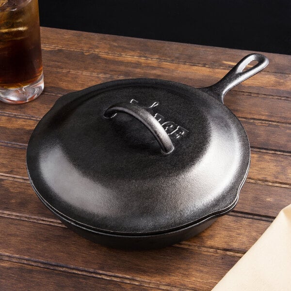 A black Lodge cast iron skillet with a handle on a wooden table.