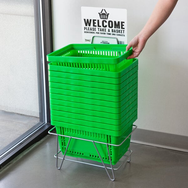 A person's hand reaching for a green Regency shopping basket with a welcome sign.