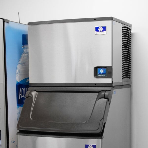 A Manitowoc water cooled ice machine with a bottle of water inside.