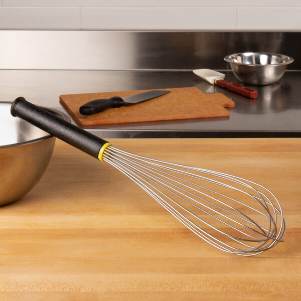 A Matfer Bourgeat stainless steel whisk with an Exoglass handle on a wooden counter.