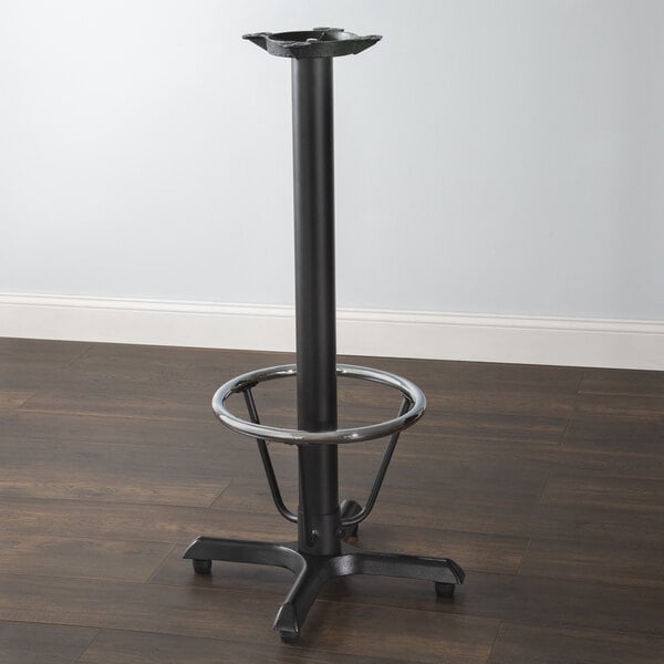A Lancaster Table & Seating black cast iron bar height table base with a round metal foot ring.