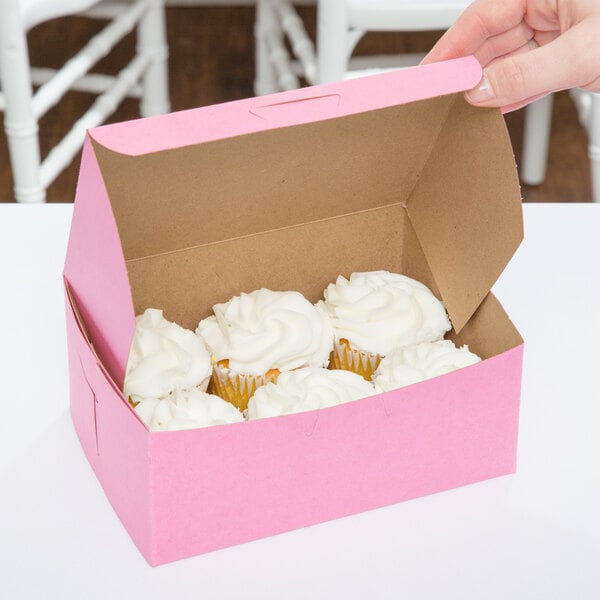 A pink bakery box with cupcakes inside.