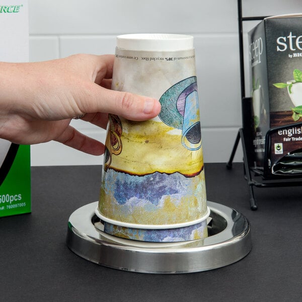 A hand using a San Jamar stainless steel in-counter cup dispenser to get a paper cup.