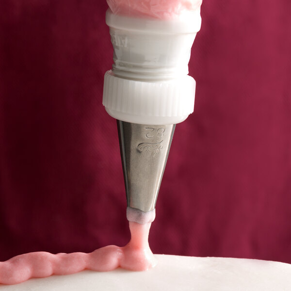 A cake being piped with an Ateco square tip using a white piping bag.