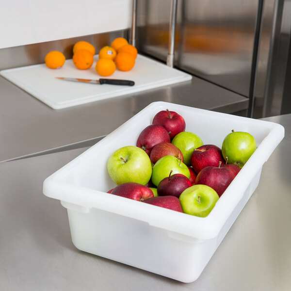 A white Carlisle food storage container full of apples on a counter.