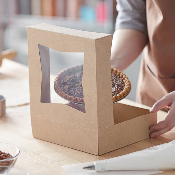 A person putting a pie into a Baker's Mark Kraft bakery box.