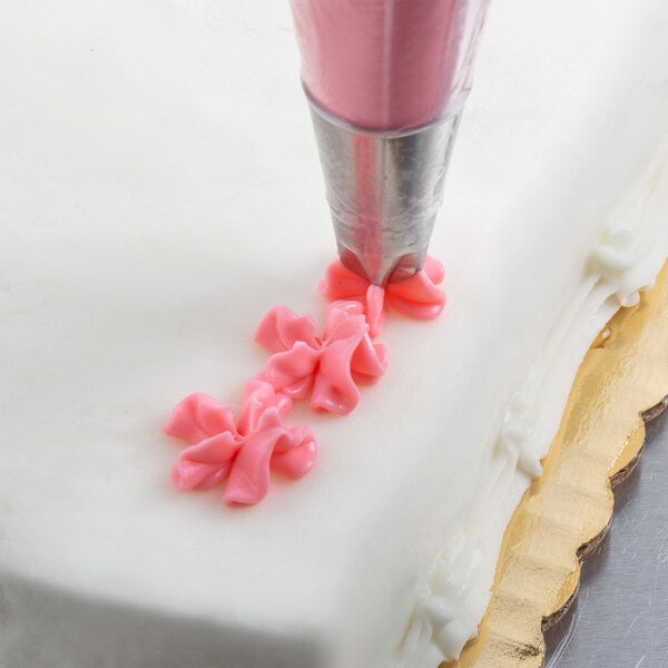 A close up of a cake with pink icing piped using an Ateco Drop Flower piping tip.