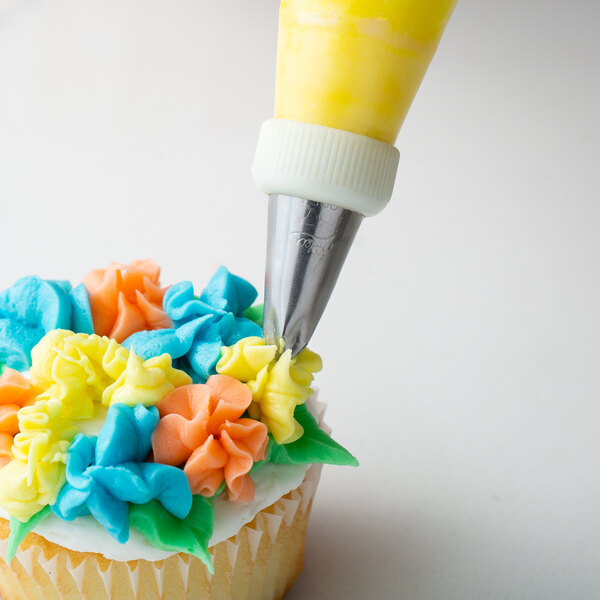 A cupcake with frosting flowers on it using a yellow and silver Ateco drop flower piping tip.