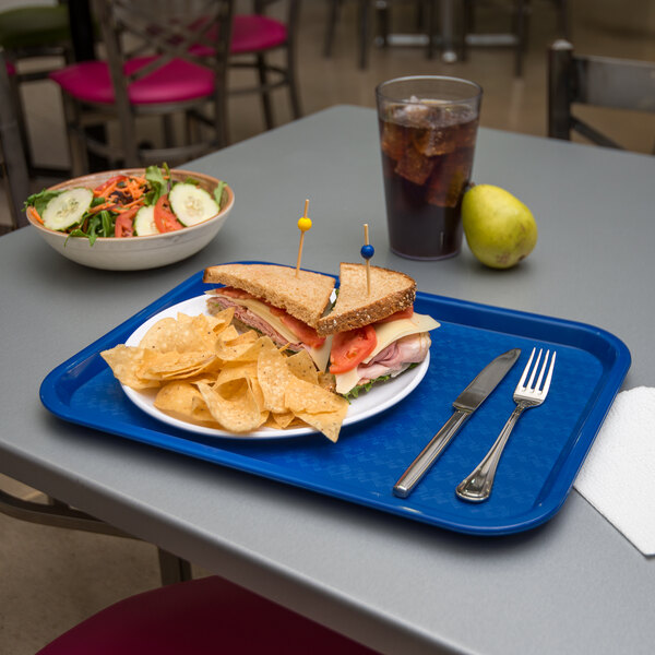 A blue Carlisle fast food tray with a sandwich and chips on it.