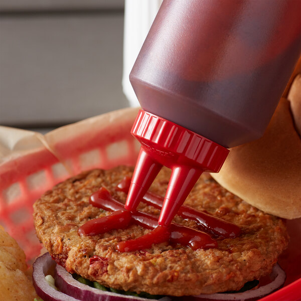 A hamburger with ketchup being poured from a Vollrath Clear Twin Tip Squeeze Bottle.
