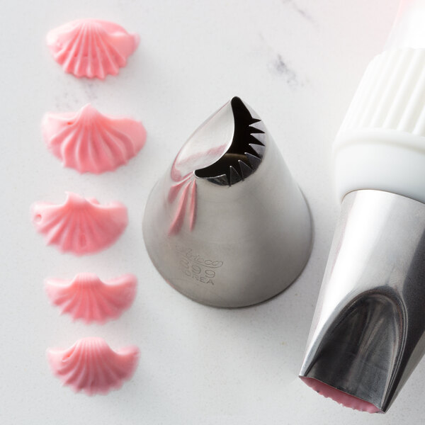 A close-up of a white Ateco curved petal piping tip with pink icing on it.