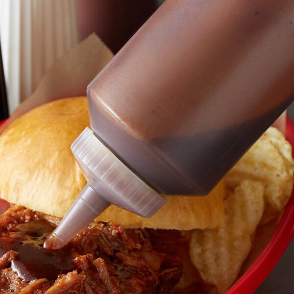 A Vollrath Color-Mate squeeze bottle of sauce on a sandwich.