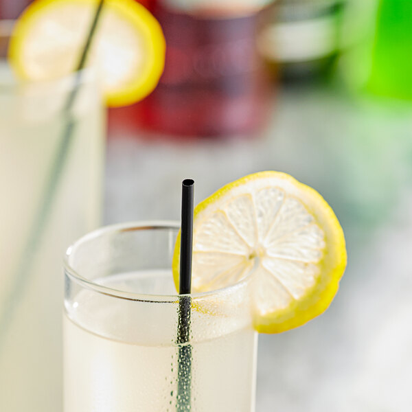 A glass of liquid with a Choice black unwrapped Collins straw and a lemon slice.