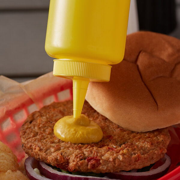 A Vollrath yellow squeeze bottle of mustard on a burger.