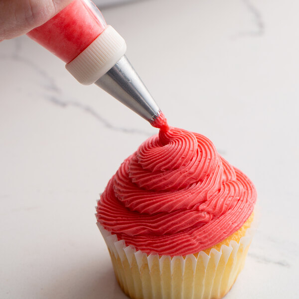 A person using an Ateco French star piping tip to frost a cupcake with pink frosting.