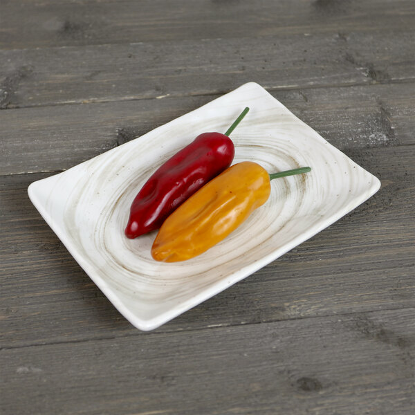 A red and yellow peppers on a white Elite Global Solutions rectangular melamine plate.