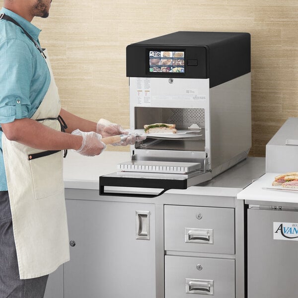 A man putting food into an ACP XpressChef 3i high speed countertop oven.