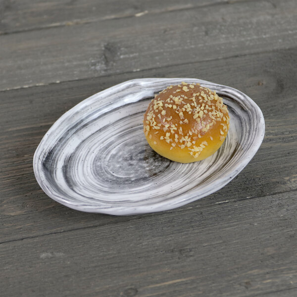 An Elite Global Solutions oval black melamine plate with a small round pastry on it.