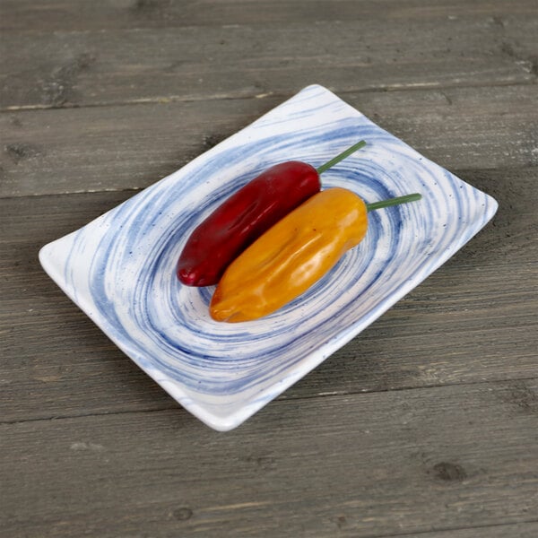 A red and yellow pepper on an Elite Global Solutions Van Gogh navy rectangular melamine plate.