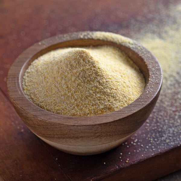 A bowl of Regal yellow cornmeal on a wooden table.