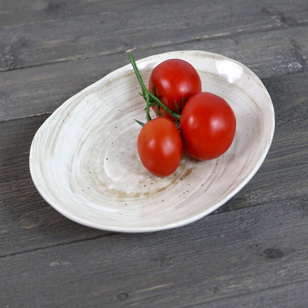 An Elite Global Solutions Van Gogh taupe melamine oval plate with two tomatoes on it.
