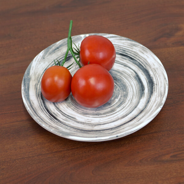 An Elite Global Solutions Van Gogh black melamine plate with tomatoes on a table.