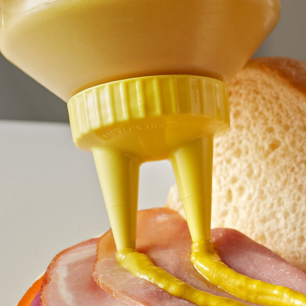 A sandwich with a Vollrath yellow Twin Tip bottle cap on a table.