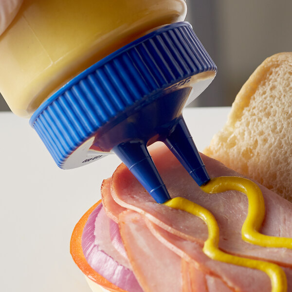 A person using a Vollrath Twin Tip Wide Mouth Bottle Cap to pour mustard onto a sandwich.