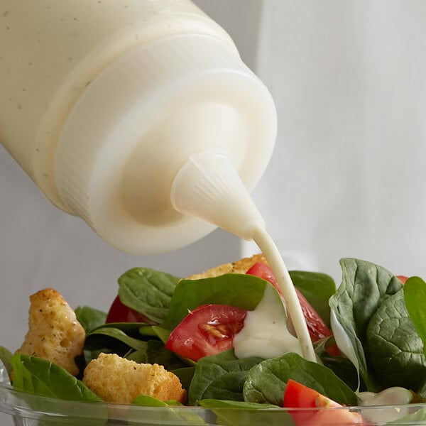 A salad with Vollrath Traex clear wide mouth bottle cap being poured over it.